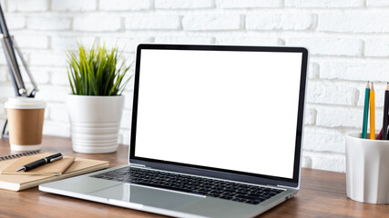 laptop computer with blank white screen, with workspace and office supplies on a wooden desk