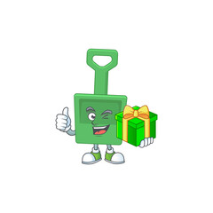 Happy smiley green sand bucket cartoon mascot design with a gift box
