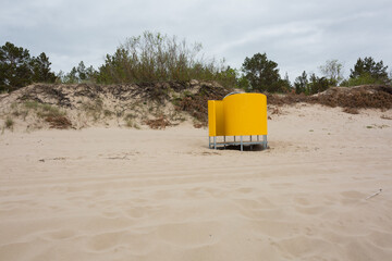 There is an outdoor dressing room in the sand by the sea.