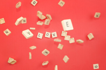 red background with scrabble pieces with the word love and pieces falling