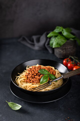 Spaghetti bolognese in a black plate on a dark background , italian cuisine. 