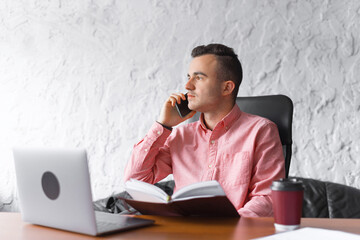 Photo of worker sitting in office and talking on phone