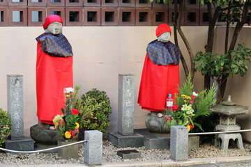 A Jizo statue dressed in a colorful costumes at a temple entrance by a street in Tokyo's Akasaka area.