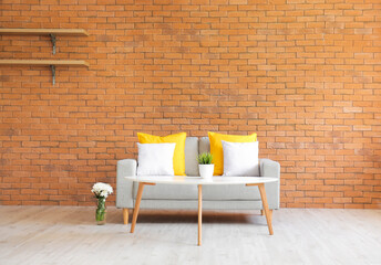 Stylish sofa and table near brick wall in living room