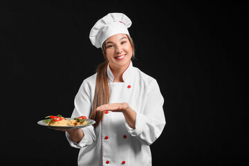 Young female chef with tasty dish on dark background