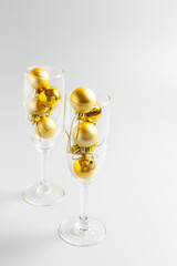  champagne glasses with golden christmas balls on gray background. New Year or Christmas concept. minimalism