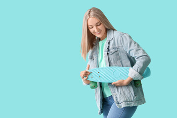 Beautiful young woman with skateboard on color background