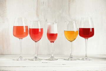 Collection of various wines and champagne in a glass arranged in a row on a white wooden rustic table. Wine tasting.