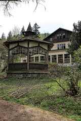 Fototapeta na wymiar Old broken windowless wooden pavillon by the devastated house