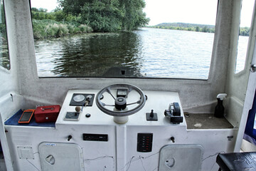 Bridge of small river ferry boat with black steering wheel