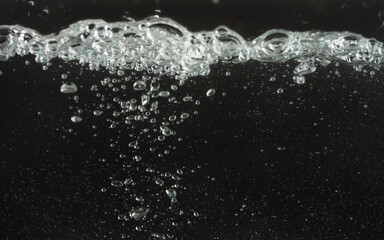 Water splashing as it's poured into aquarium tank, black background