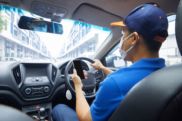Asian delivery man courier online using mobile phone contact the customer. He wears a mask to...