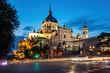 Fototapeta na wymiar Cathedral of Saint Mary the Royal of La Almudena in center of Madrid at night. View from the crossroad with car lights.