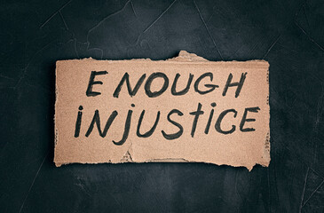 Enough injustice text on cardboard on dark background