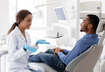 Smiling woman dentist doctor discussing treatment with patient
