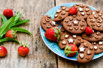    Fresh organic strawberries and cocoa cookies with  vanilla star decoration on wooden background. Summer dessert