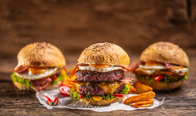 Juicy and tasty burgers menu with double beef burger in the front with spicy potato wedges and chilli and two more burgers in the back