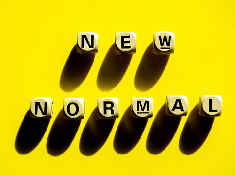 New Normal, word on wooden alphabet cube on yellow background, minimal style.