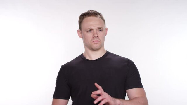 Athletic caucasian man looking around feeling disgusted and surprised on a white studio backdrop