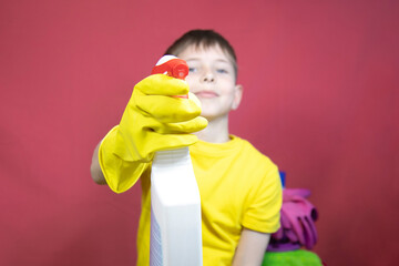 A boy in yellow gloves with cleaning products 