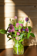 Red clover bouquet in class vase on windowsill. Trifolium pratense
