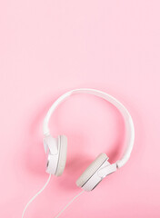 White headphones on pink background. Top view to the music. Around it is quiet, inside is loud. Respect for foreign borders.