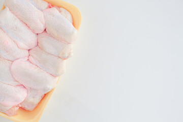 Fresh chicken wings in a plate on a white marble table with copy space. Raw chicken wings on a white background