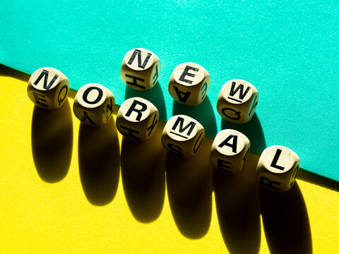 New Normal, word on wooden alphabet cube on light green and yellow background, minimal style.
