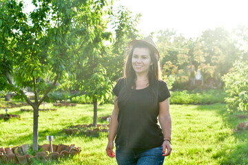 Smiling happy  young  woman gardener in an  organic  orchar apple garden in a sunny day