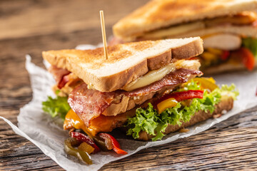 Club sandwich on a rustic table witch chicken, bacon, pepper and lettuce