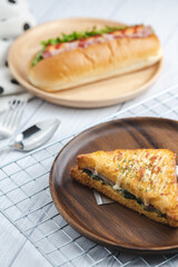 croque monsieur with slices of boiled ham, placed on a wooden plate with cooking tools.