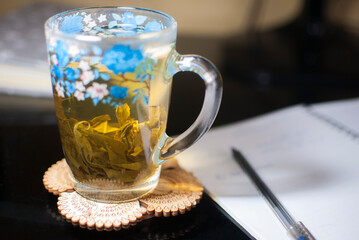 Transparent cup with blue flowers and green tea