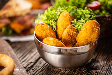 Chicken nuggets with salad in a metal bowl on a rustic wooden surface