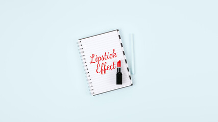 Lipstick Effect concept with Red Lipstick and open notebook with text on blue background