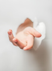 Naklejka premium The girls hand is hiding behind a sheet of paper. Hand through a hole in paper