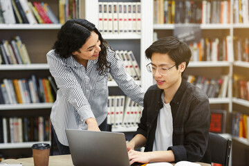 Mexican counselor standing and looking at student's work