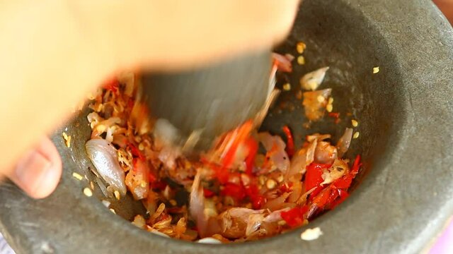Pounding  chili with garlic in mortar , in door  Chiangmai Thailand