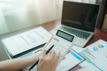 Businesswoman working from home with a calculator and financial report on wooden table.