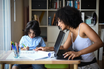 Fototapeta na wymiar metis woman working home with her son doing his homework