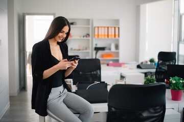 Girl at work, using her phone. Beautiful businesswoman in office.	