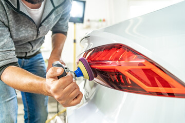 hand polishing car headlights with the help of a hand grinder for better shine