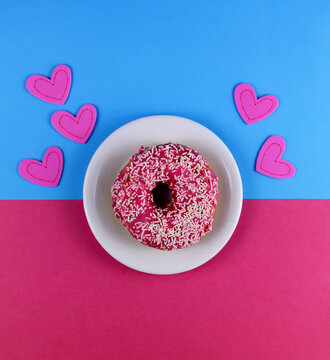 Pink donut on a plate top view stock images. Doughnut with icing on a blue and pink background. Donut with hearts stock images. American delicacy food