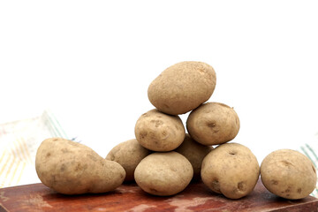 Pile of unpeeled potatoes above wood cutting board
