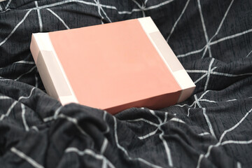Small blank cardboard clothing box above wrinkle material
