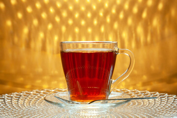 A cup of tea is standing on a glass tray.