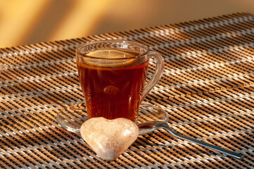 A cup with tea, lemon and pastries stands on a table covered with a mat.