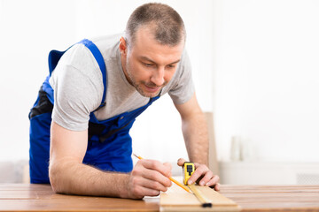 Professional Carpenter Measuring Wooden Board Working Indoors, Selective Focus