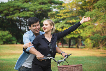 Fototapeta premium Young couple walking their bike along happily talking in park
