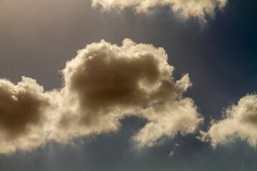 Beautiful puffy clouds backlit by the sun on a blue sky.