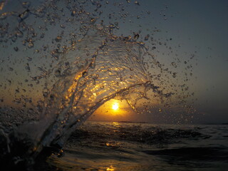 Silhouette of water splash at sunset, next to the sea